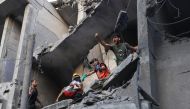 Palestinian civil defence members and others carry a child killed in an Israeli bombardment from a building in Khan Yunis on the southern Gaza Strip on October 19, 2023. Photo by Mahmud HAMS / AFP