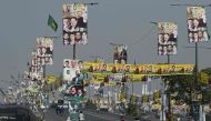 Commuters drive along a road past banners with the image of Pakistan's former Prime Minister Nawaz Sharif and Pakistan Muslim League (Nawaz) party leaders in Lahore on October 21, 2023. (Photo by Aamir Qureshi / AFP)