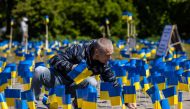 A man sticks a flag beside other Ukrainian flags, during a protest organized by activists of the Ukrainian diaspora in Warsaw, on May 9, 2023. (Photo by Wojtek Radwanski / AFP)