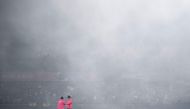 Field umpires stand on the pitch as fog hovers over the field during the 2023 ICC Men's Cricket World Cup one-day international (ODI) match between India and New Zealand at the Himachal Pradesh Cricket Association Stadium in Dharamsala on October 22, 2023. (Photo by Money SHARMA / AFP)