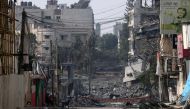 A man sits in front of buildings destroyed by Israeli strikes in Gaza City on October 28, 2023. Photo by MOHAMMED ABED / AFP
