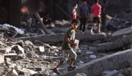 Palestinians walk on the rubble of buildings destroyed by Israeli bombardment in the Nuseirat refugee camp, in the central Gaza Strip on October 30, 2023, amid the ongoing battles between Israel and Hamas. Photo by MOHAMMED ABED / AFP