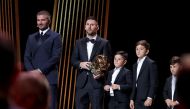 Lionel Messi (C) reacts with his trophy next to his children on stage as he receives his 8th Ballon d'Or award next to Former English football player and Inter Miami's co-owner David Beckham (L). (Photo by Franck Fife / AFP)