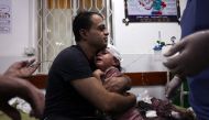 Palestinian man cradles an injured child at the Najjar hospital following an Israeli air strike on a home in Rafah on October 30, 2023. Photo by Said KH / AFP