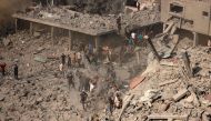 People check buildings destroyed in an Israeli strike on the Bureij refugee camp in the central Gaza Strip yesterday. (AFP)