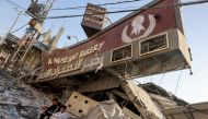 A Palestinian man and his son sit holding a bag of bread outside a destroyed bakery at the Nuseirat refugee camp in the central Gaza Strip on November 4, 2023. Photo by MOHAMMED ABED / AFP