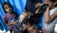 A wounded Palestinian woman from the Baraka family is surrounded by her children upon their arrival at Nasser Hospital in Khan Yunis in the southern Gaza Strip following Israeli air strikes that hit their building on November 13, 2023. Photo by Mahmud HAMS / AFP