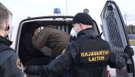 Border guards place asylum seekers that had crossed over from Russia into a van to be transported to a reception centre from the Nuijamaa border station between Russia and Finland in Lappeenranta, south eastern Finland early morning on November 16, 2023.  (Photo by Vesa Moilanen / Lehtikuva / AFP) 