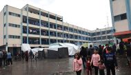 Internally displaced Palestinian children living in a school run by the UN agency for Palestinian refugees (UNRWA), walks across a wet courtyard following overnight rainstorms in Rafah in the southern Gaza Strip on November 15, 2023. Photo by SAID KHATIB / AFP