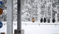 Finnish Border Guards escort two migrants at the Raja-Jooseppi international border crossing station in Inari, northern Finland, on November 27, 2023. (Photo by Emmi Korhonen / Lehtikuva / AFP) / Finland OUT
