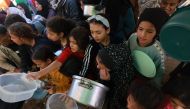 Displaced Palestinian children queue for food and bread donations in the southern Gaza Strip city of Rafah, on November 30, 2023. Photo by MOHAMMED ABED / AFP