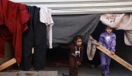 Displaced Palestinian girls stand at the entrance of street shops used as temporary shelter in Rafah in the southern Gaza Strip on December 10, 2023. Photo by MOHAMMED ABED / AFP