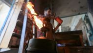 A shopkeeper lights a kerosene pressure stove in Rafah in the southern Gaza Strip on December 9, 2023. (Photo by Mahmud Hams / AFP)
