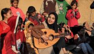 Ruaa Hassouna plays music for Palestinian children on her Oud (Ud, or oriental lute) as Palestinian children participate in an activity aimed to support their mental health on December 18, 2023. (Photo by Said Khatib / AFP)