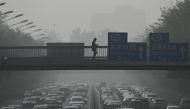 Pedestrians walk on an overpass as traffic snarls amid haze from air pollution in Beijing on November 1, 2023. Photo by Pedro PARDO / AFP