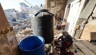A woman washes clothes in her destroyed house in Rafah in the southern Gaza Strip on December 18, 2023. (Photo by Mohammed Abed / AFP)
