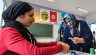 A voter is assisted to dip her finger in ink after voting at a polling station during the 2023 local elections on the outskirts of Tunis on December 24, 2023. (Photo by Fethi Belaid / AFP)