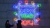 People take pictures in front of a light display reading 