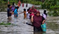 A woman carries her belongings as she walks through floodwaters following heavy rain in Thailand's southern province of Narathiwat on December 25, 2023. Photo by Madaree TOHLALA / AFP