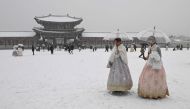 Visitors wearing traditional hanbok dress walk in the snow at Gyeongbokgung palace in central Seoul on December 30, 2023. (Photos by Jung Yeon-je / AFP)