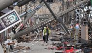 People walk past fallen utility poles and damaged buildings in the city of Wajima, Ishikawa prefecture on January 4, 2024, after a major 7.5 magnitude earthquake struck the Noto region in Ishikawa prefecture on New Year's Day. Photo by Kazuhiro NOGI / AFP
