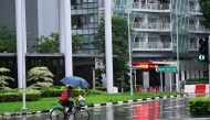  A man holding an umbrella rides in rain in Singapore, Jan. 4, 2024. (Photo by Then Chih Wey/Xinhua)
