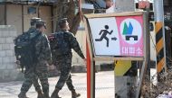 South Korean marines walk past a shelter sign in a village of Yeonpyeong island, near the 'northern limit line' sea boundary with North Korea, on January 6, 2024. (Photo by Jung Yeon-je / AFP)