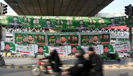 Commuters ride past banners of Pakistan's political parties displayed along a street in Rawalpindi on January 15, 2024. (Photo by Aamir Qureshi / AFP)
