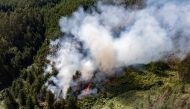 This aerial view shows smoke billowing from a forest fire in Nemocon, Colombia on January 24, 2024. (Photo by Luis Acosta / AFP)