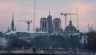 This photograph taken on February 12, 2024, shows illuminated construction site of Notre-Dame de Paris Cathedral with its rear spire, in Paris. (Photo by Ludovic MARIN / AFP)
