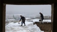 Afghan men shovel snow from the rooftop of a house following snowfall in Fayzabad, Badakhshan province on February 19, 2024. (Photo by Omer Abrar / AFP)