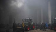 Farmers gather near a tractor as smoke rises during a protest called by the farmers' organizations 