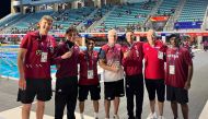 Qatar's swimmers along with the officials celebrate with their medals.  