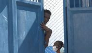 This screen grab taken from AFPTV shows a person looking out from behind a door near the main prison of Port-au-Prince, Haiti, on March 3, 2024, after a breakout by several thousand inmates. (Photo by Luckenson JEAN / AFPTV / AFP)
