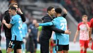 Bayer Leverkusen's Spanish head coach Xabi Alonso (2nd L) embraces Bayer Leverkusen's French forward #21 Amine Adli (R) after the German first division Bundesliga football match SC Freiburg v Bayer 04 Leverkusen in Freiburg, southwestern Germany on March 17, 2024. (Photo by THOMAS KIENZLE / AFP)