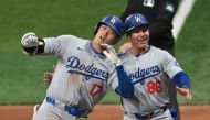 Los Angeles Dodgers' Shohei Ohtani (L) celebrates with 1B coach Clayton McCullough (R) on first base after hitting a RBI single during the eighth inning of the 2024 MLB Seoul Series baseball game between Los Angeles Dodgers and San Diego Padres at the Gocheok Sky Dome in Seoul on March 20, 2024. (Photo by Jung Yeon-je / AFP)