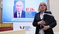 Russia's Central Electoral Commission (CEC) head Ella Pamfilova walks past a screen displaying a portrait of re-elected Russian President Vladimir Putin following the announcement of the official results in the three-day presidential election in Moscow on March 21, 2024. (Photo by Stringer / AFP)