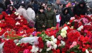 People lay flowers at a makeshift memorial in front of the Crocus City Hall in Krasnogorsk on March 24, 2024, as Russia observes a national day of mourning after a massacre that killed more than 130 people. Photo by Olga MALTSEVA / AFP.