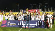 Al Bidda's players and officials celebrate with the trophy.
