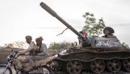 RSF soldiers ride a motorcycle on a main street in El Geneina past a destroyed tank that belonged to the Sudanese military. Photo by Diana Zeyneb Alhindawi
