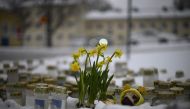 Candles and flowers are placed in the snow in front of the Viertola School to pay tribute to victims in Vantaa, in the north of the Finnish capital Helsinki, on April 3, 2024, one day after a 12-year-old opened fire inside the school, killing a classmate and seriously injuring two other children. Photo by Olivier MORIN / AFP