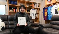 (Files) This photo taken on January 30, 2023 shows Japanese cartoonist and manga artist Yoichi Takahashi displaying his autograph with the painting of the main character following an interview with AFP at his workplace in Tokyo. (Photo by Kazuhiro Nogi / AFP)