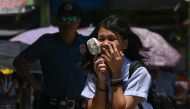 A student uses a portable fan outside a school in Manila on April 2, 2024. Photo by JAM STA ROSA / AFP
