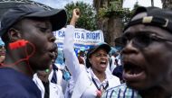 A Kenyan doctor gestures outside the health ministry headquarters while protesting with placards to demand better pay and working conditions in the capital, Nairobi on April 9, 2024. Photo by SIMON MAINA / AFP
