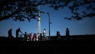People gather under the blooming cherry blossoms with the background of the landmark Tokyo Skytree (C) at Sumida Park, near the famous tourism spot of Asakusa district in Tokyo on April 10, 2024. (Photo by Philip FONG / AFP)

