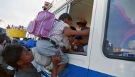 (FILES) A Haitian woman pushes her son through the window of a bus leaving for the countryside from Port-au-Prince on September 16, 1994. (Photo by Thony BELIZAIRE / AFP)
