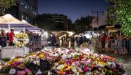 Members of the public look at flowers placed outside the Westfield Bondi Junction shopping mall in Sydney on April 14, 2024, the day after a 40-year-old knifeman with mental illness roamed the packed shopping centre killing six people and seriously wounding a dozen others. (Photo by DAVID GRAY / AFP)
