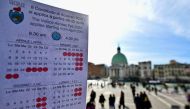 A person shows a calendar of the paying days to visit Venice, on April 19, 2024 in front of Santa Lucia train station in Venice. (Photo by Gabriel Bouys / AFP)