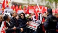 A protestor holds a sign and roses during a demonstration called in support of the Spanish Prime Minister, in front of the PSOE party headquarters in Madrid, on April 27, 2024. (Photo by OSCAR DEL POZO / AFP)
