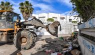 A bulldozer clears debris outside the International Organisation for Migration (IOM) headquarters in Tunis on May 3, 2024 after the local authorities removed an encampment that was erected there by migrants in a forced evacuation. (Photo by FETHI BELAID / AFP)
